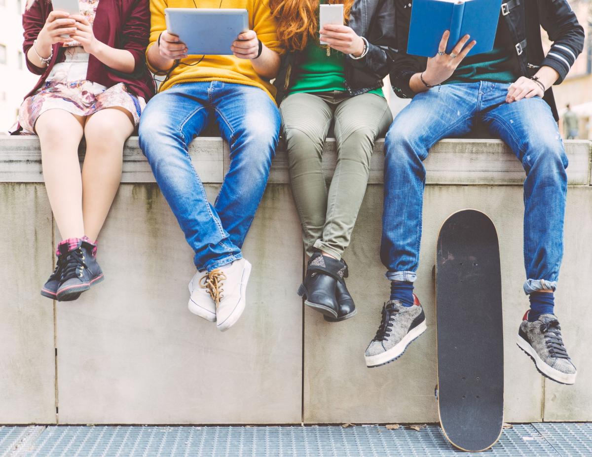 teens sitting on a wall with media devices